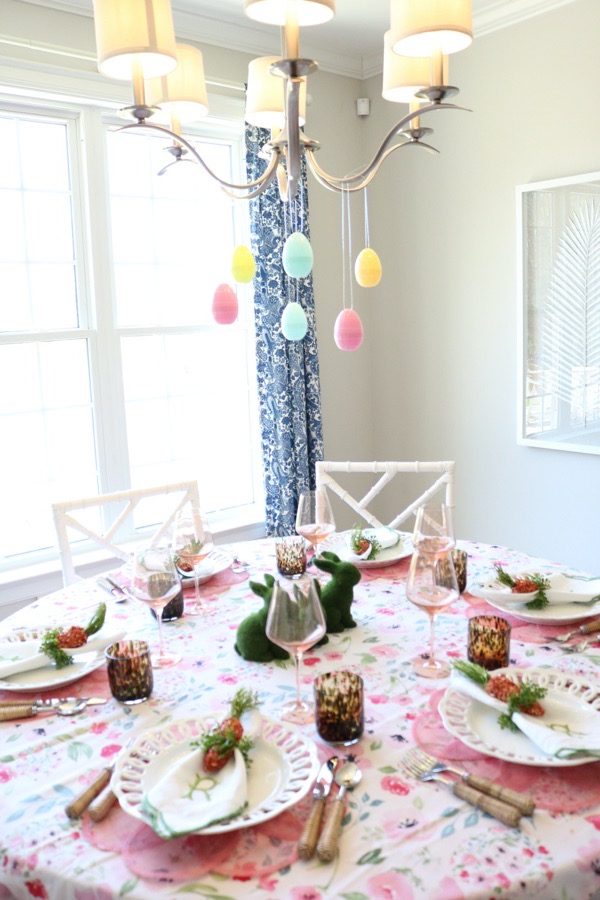 Colorful Easter eggs hang from a chandelier over an Easter brunch tablescape.