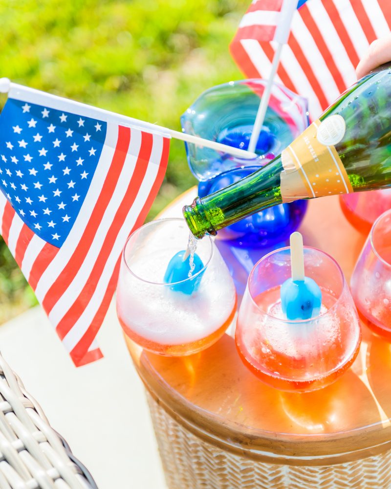 Taylor pours champagne into glasses with bomb popsicles in them to create a pop-tail for guests. 